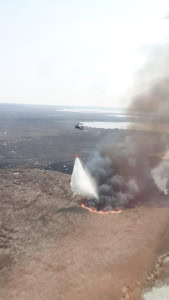 Zwei S-70 "Black Hawk"-Hubschrauber im Kampf gegen einen Schilfbrand.